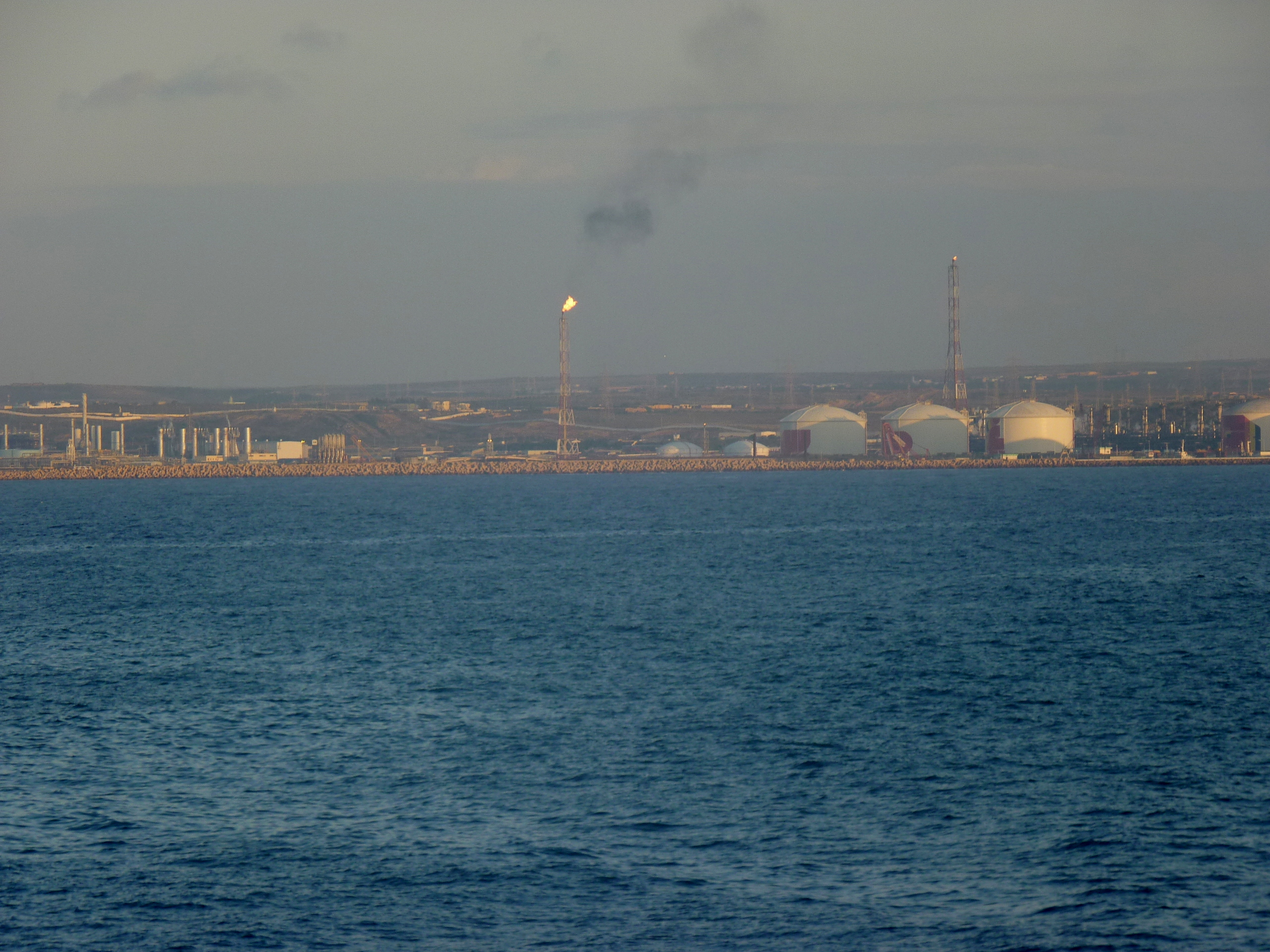 A gas terminal on the Algerian coast at dusk, seen from the sea